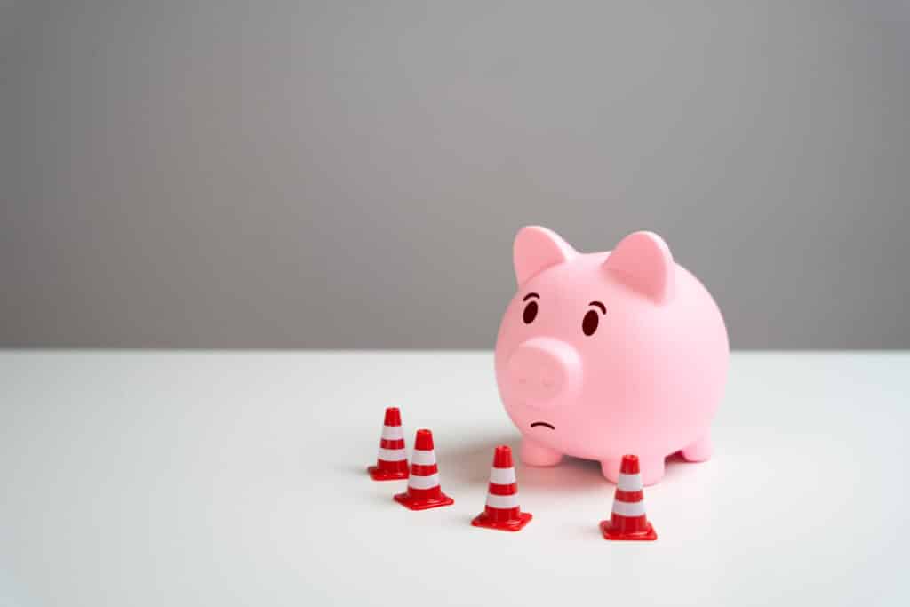 Traffic cones blocking a piggy bank, symbolizing setting financial boundaries